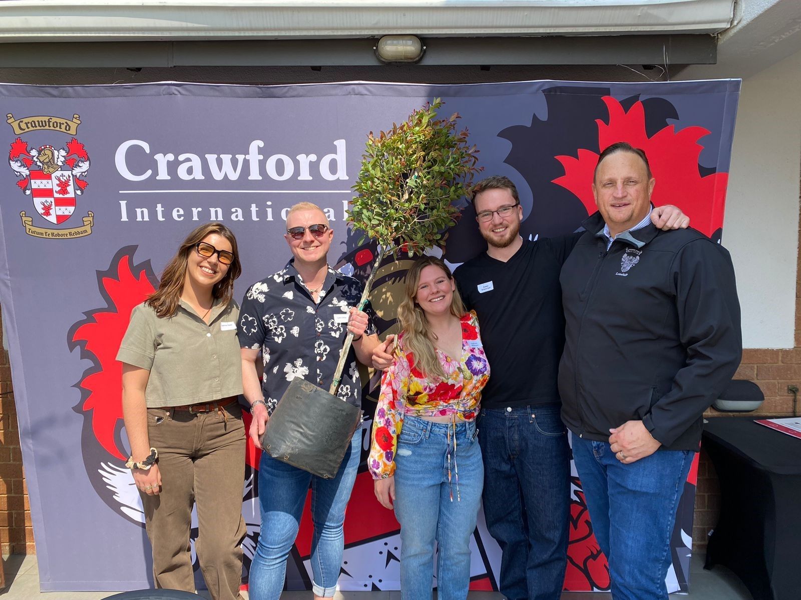 A group of people are posing for a picture in front of a crawford international sign.