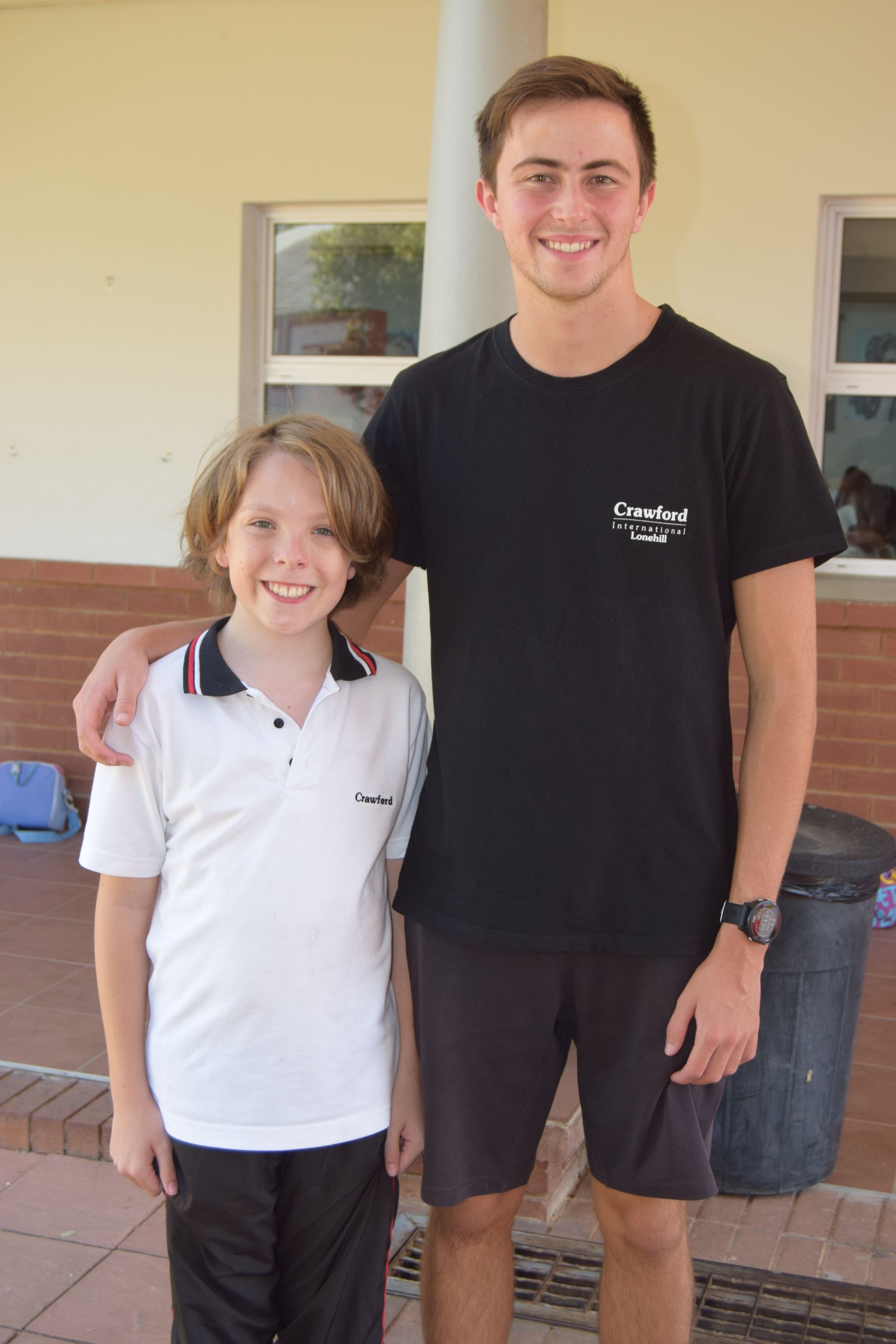 A man and a boy are standing next to each other and smiling.