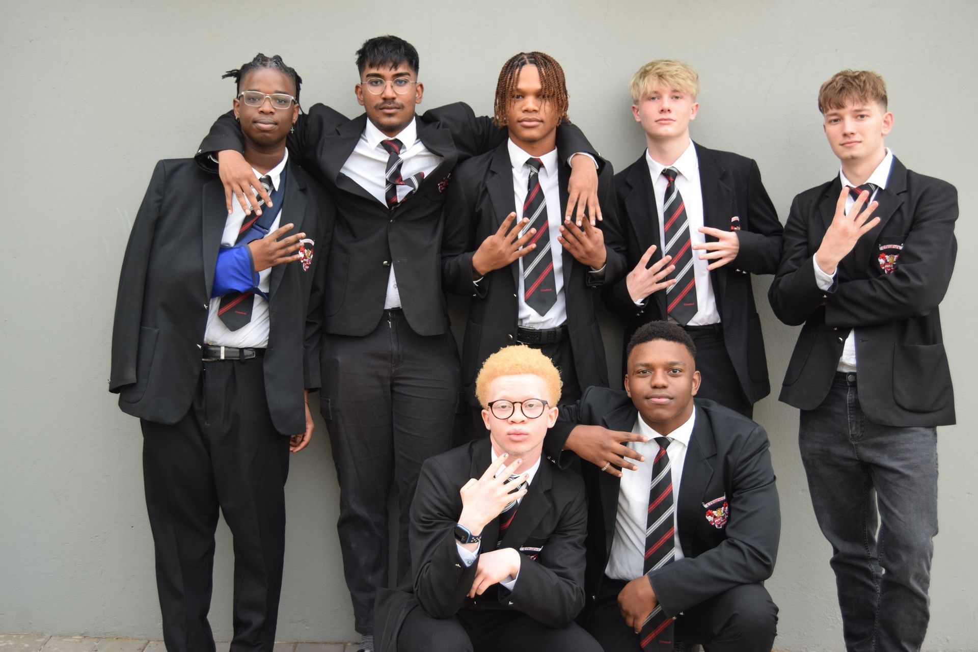 A group of young men in suits and ties are posing for a picture.
