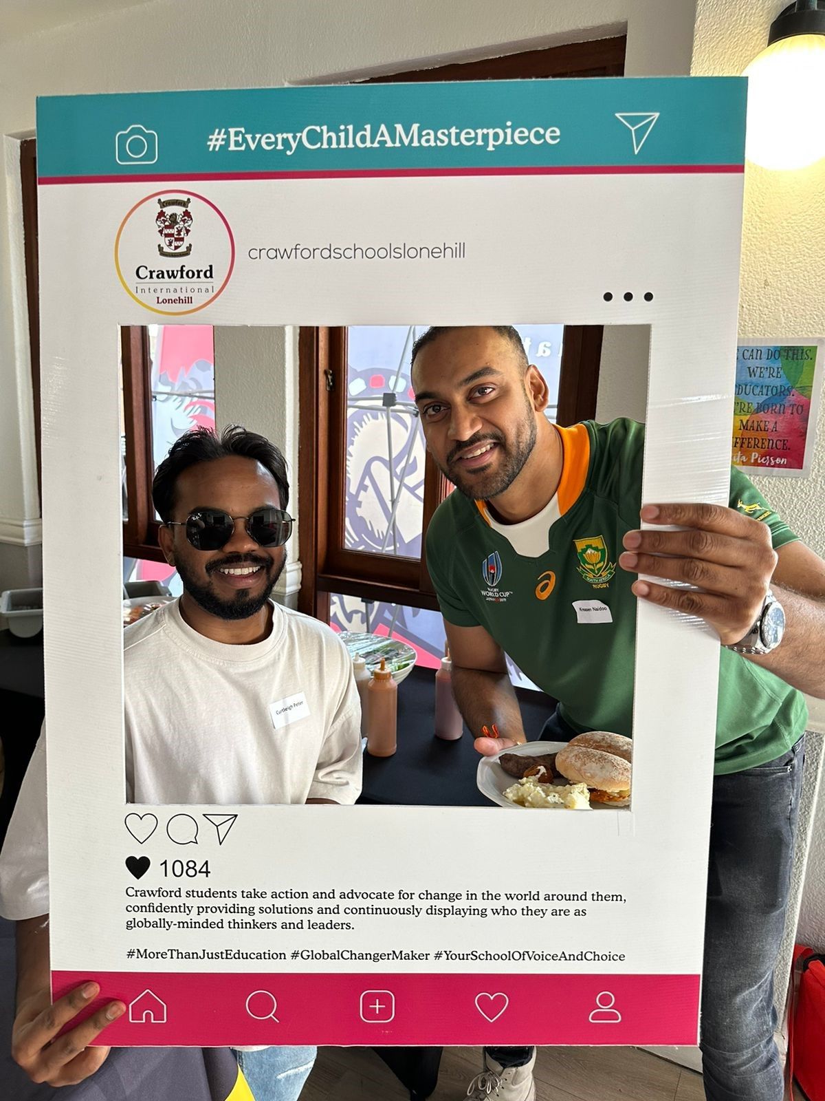 Two men are standing next to each other holding a picture frame.