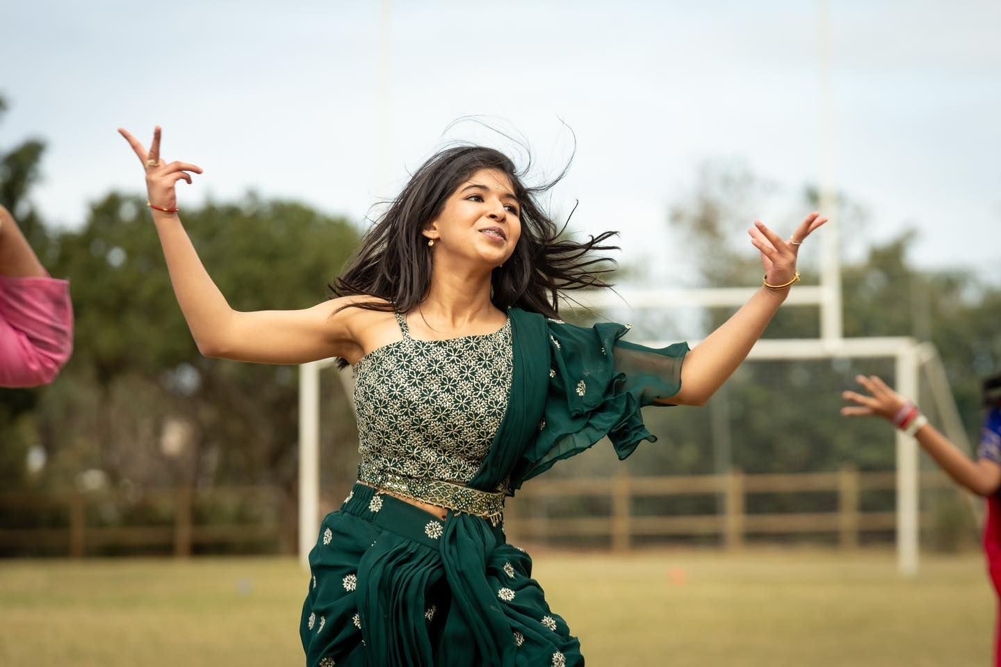 A woman in a green dress is dancing on a field.