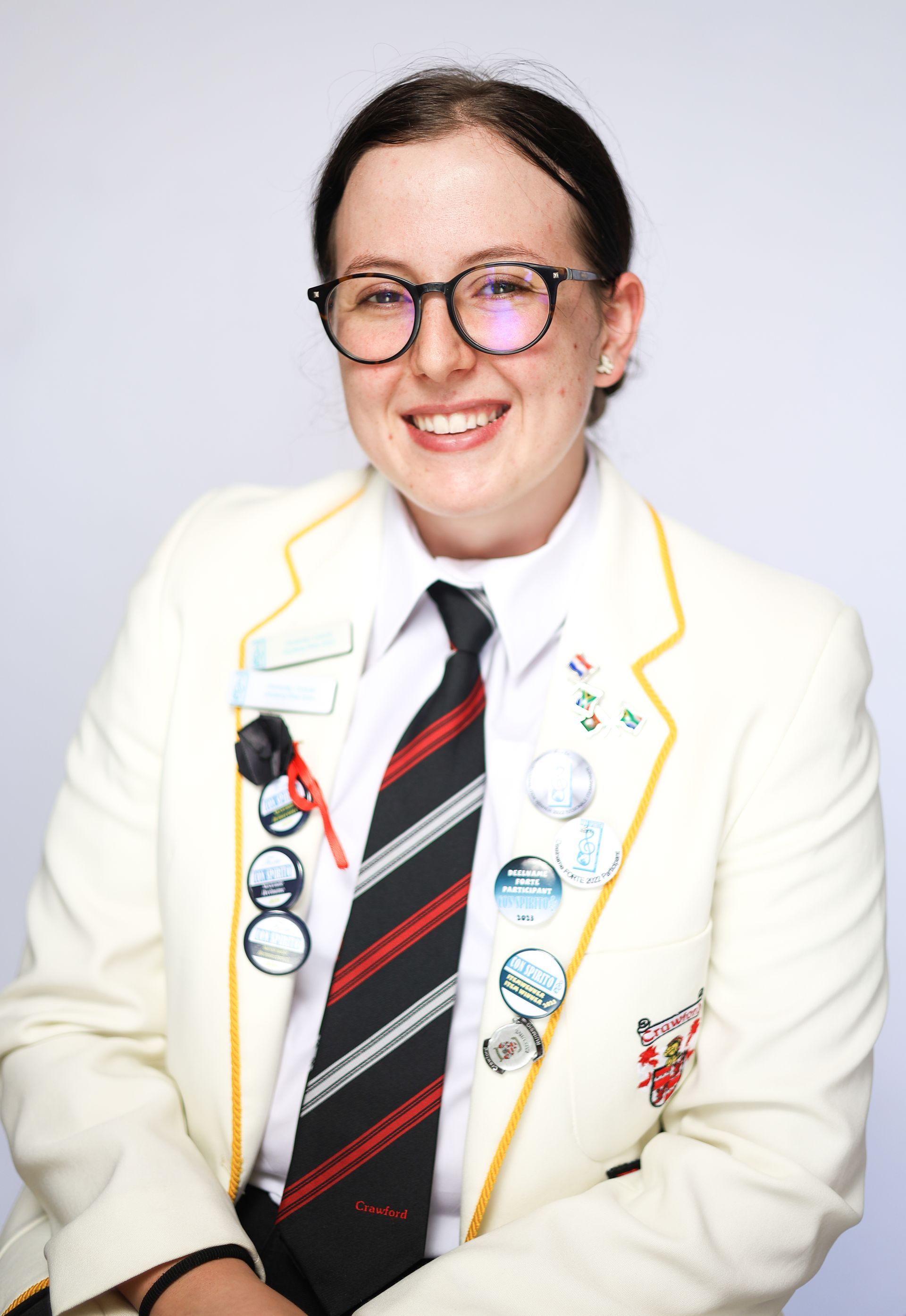 A woman wearing glasses and a tie is smiling for the camera