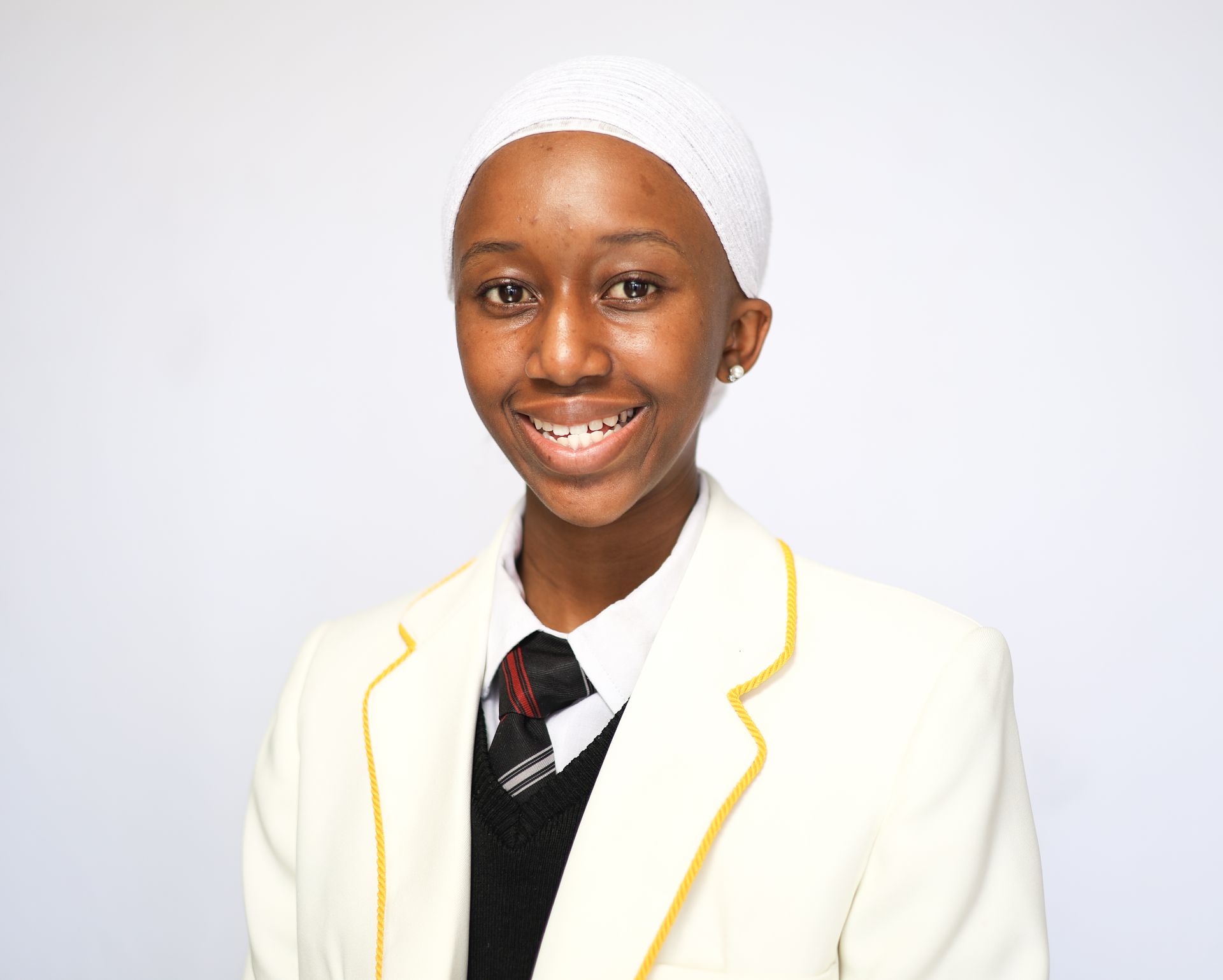 A young woman wearing a white hat and a white jacket is smiling.