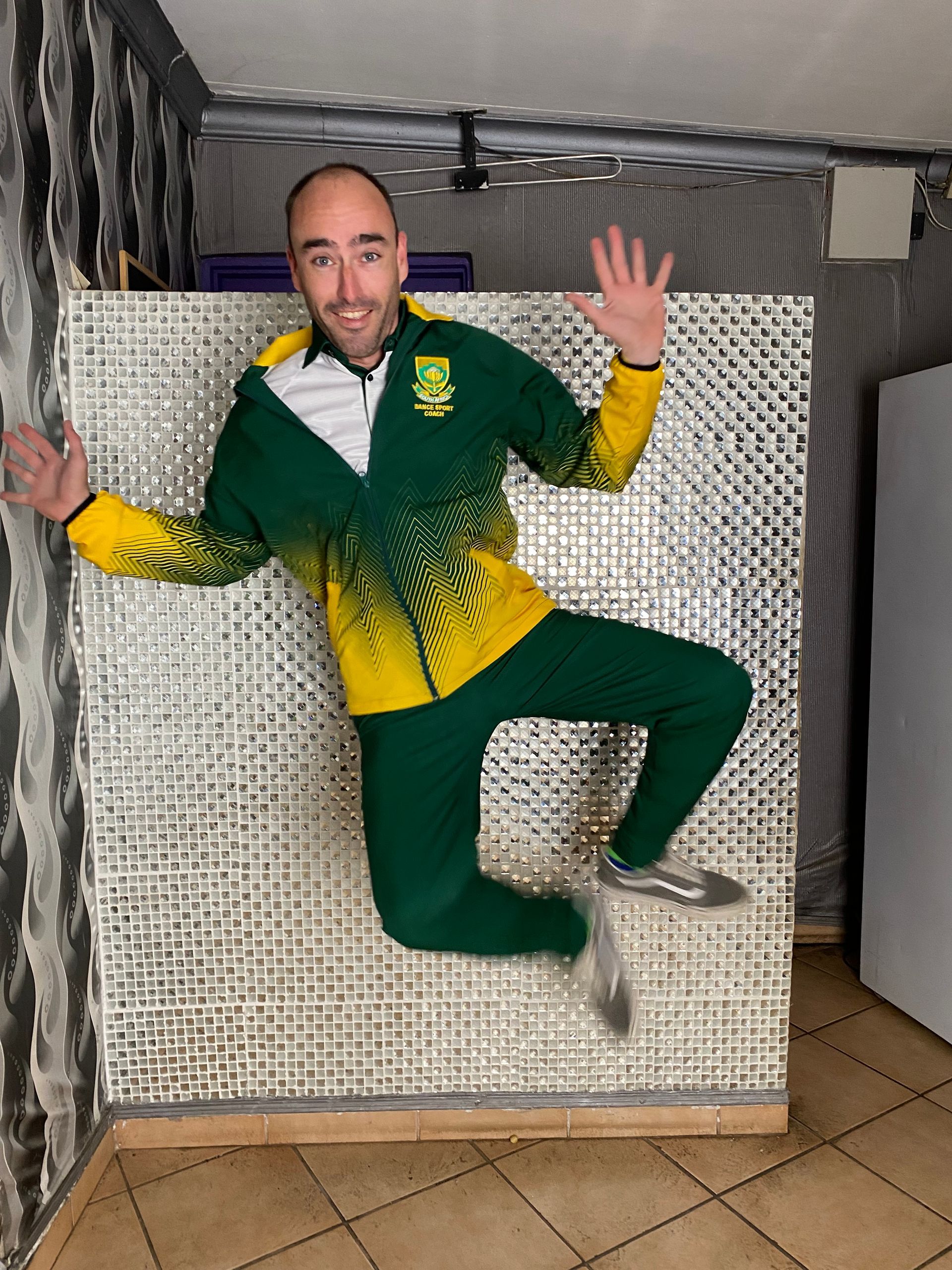 A man in a green and yellow jacket is jumping in the air.