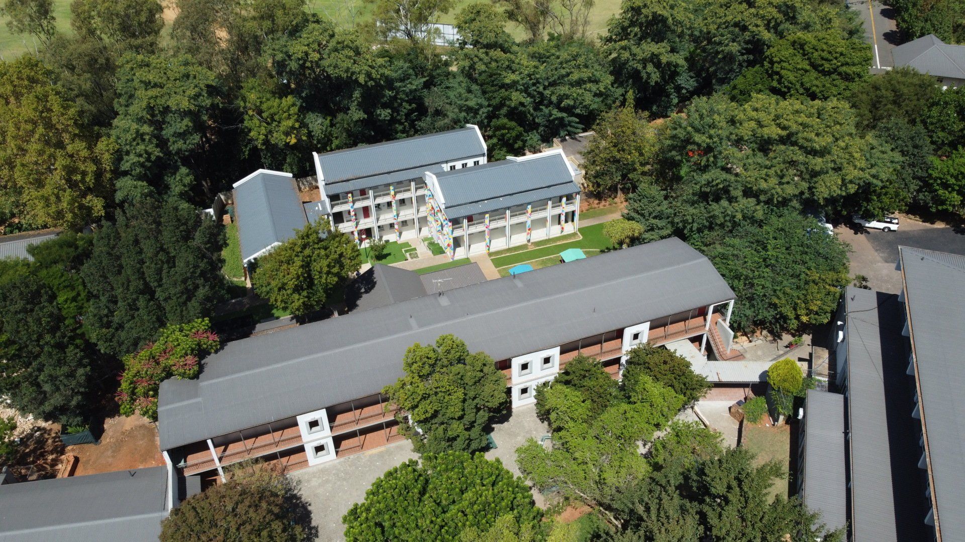 an aerial view of the campus building surrounded by trees .