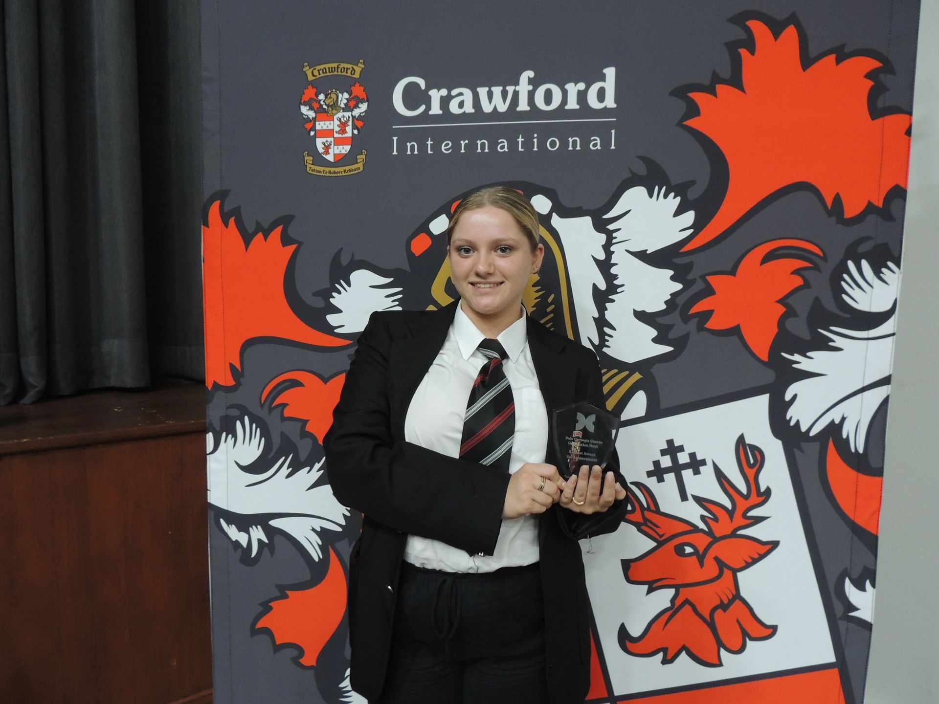 A woman stands in front of a crawford international banner