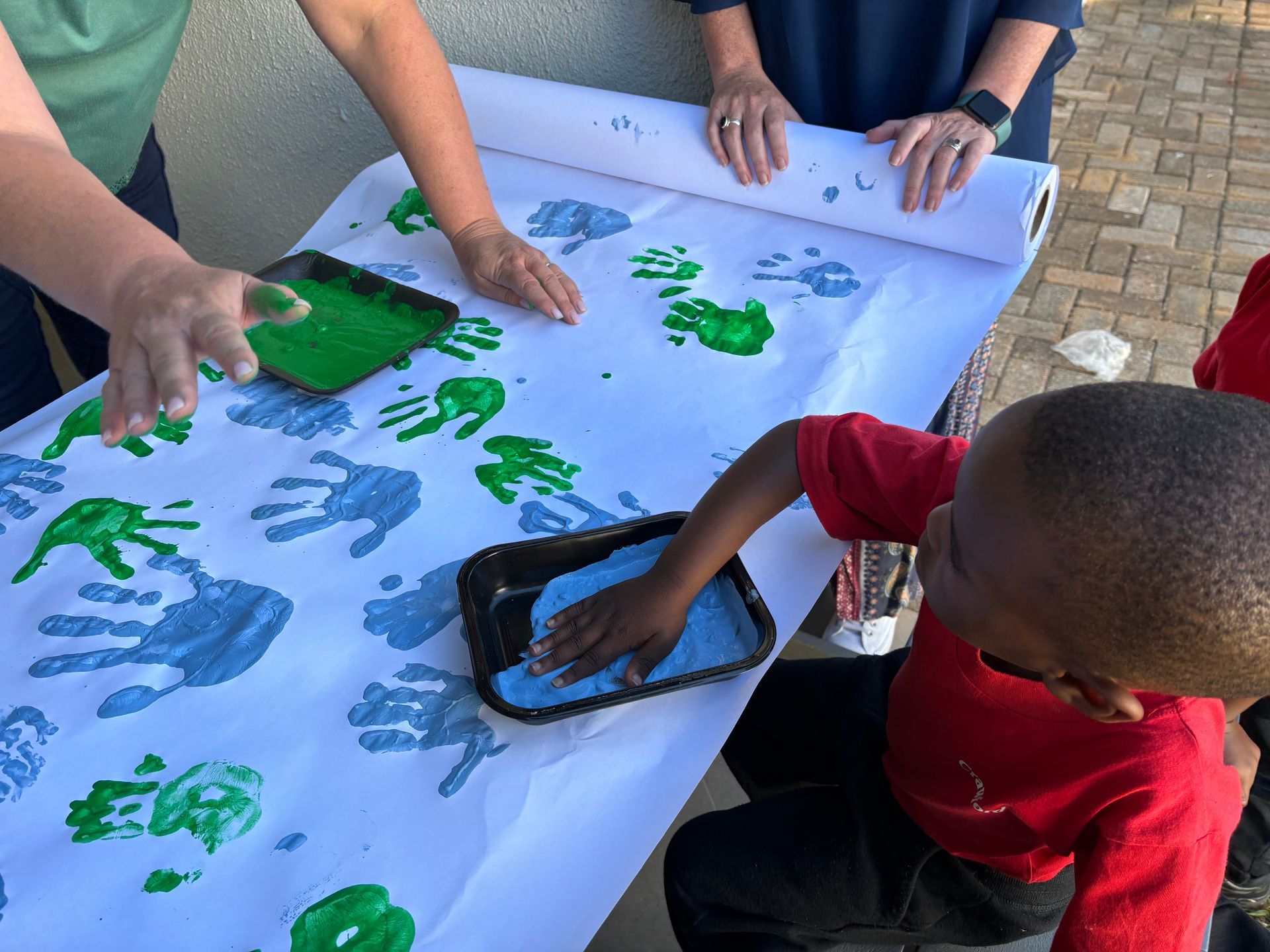 A boy is sitting at a table with his hands painted green
