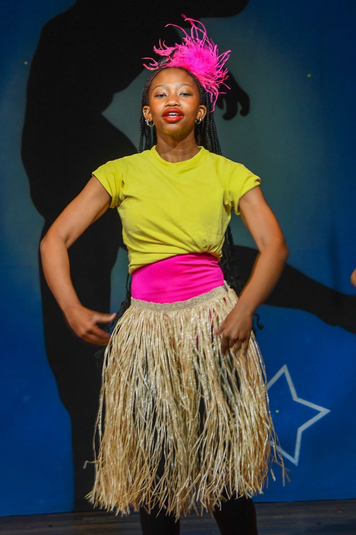 A girl wearing a yellow shirt and a straw skirt