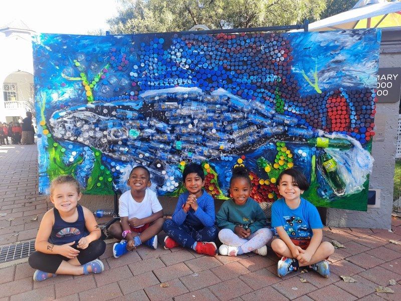 A group of children are sitting in front of a painting of a whale