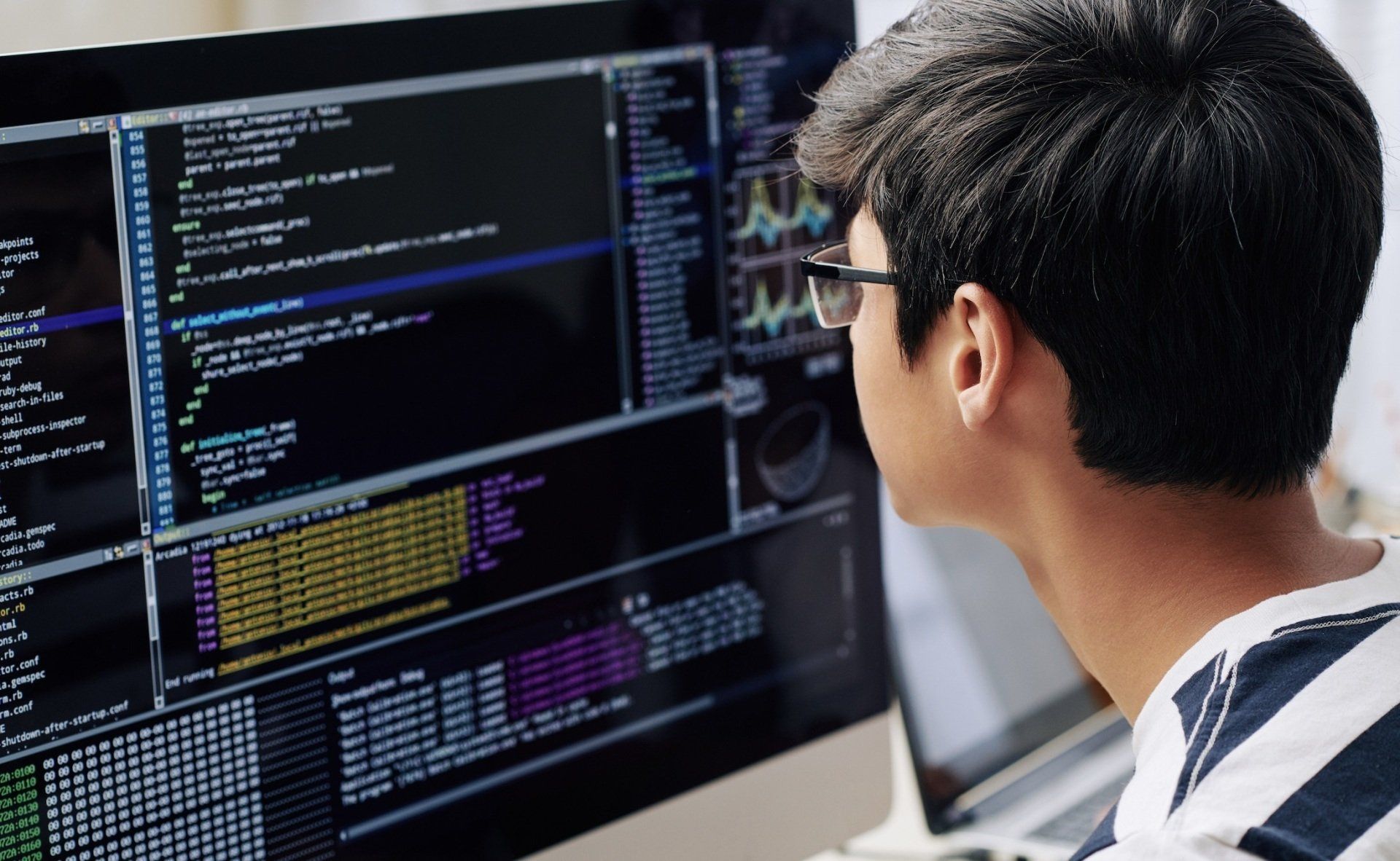 A man wearing glasses is looking at a computer screen.