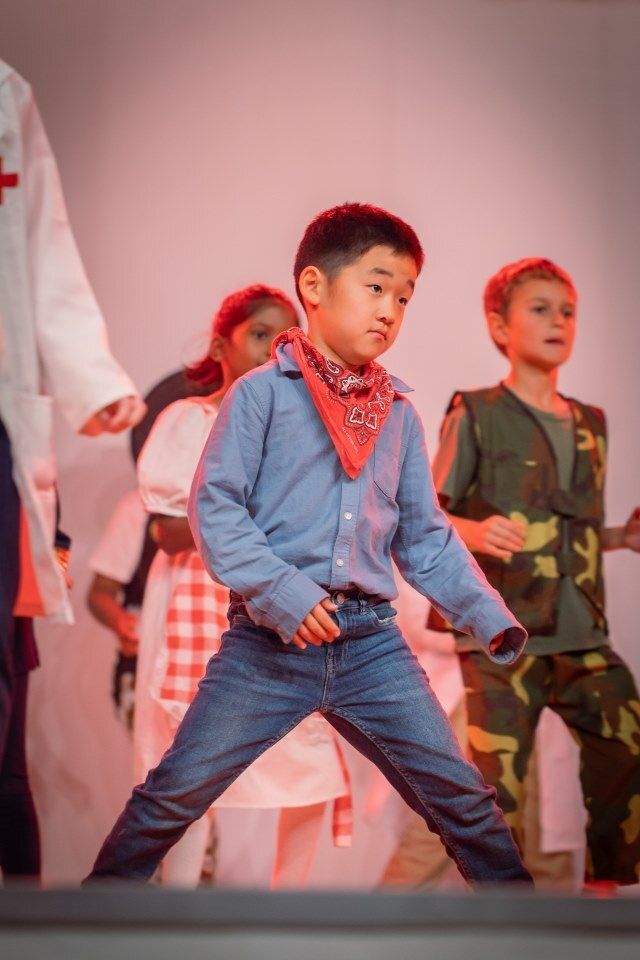 A group of children are dancing on a stage.