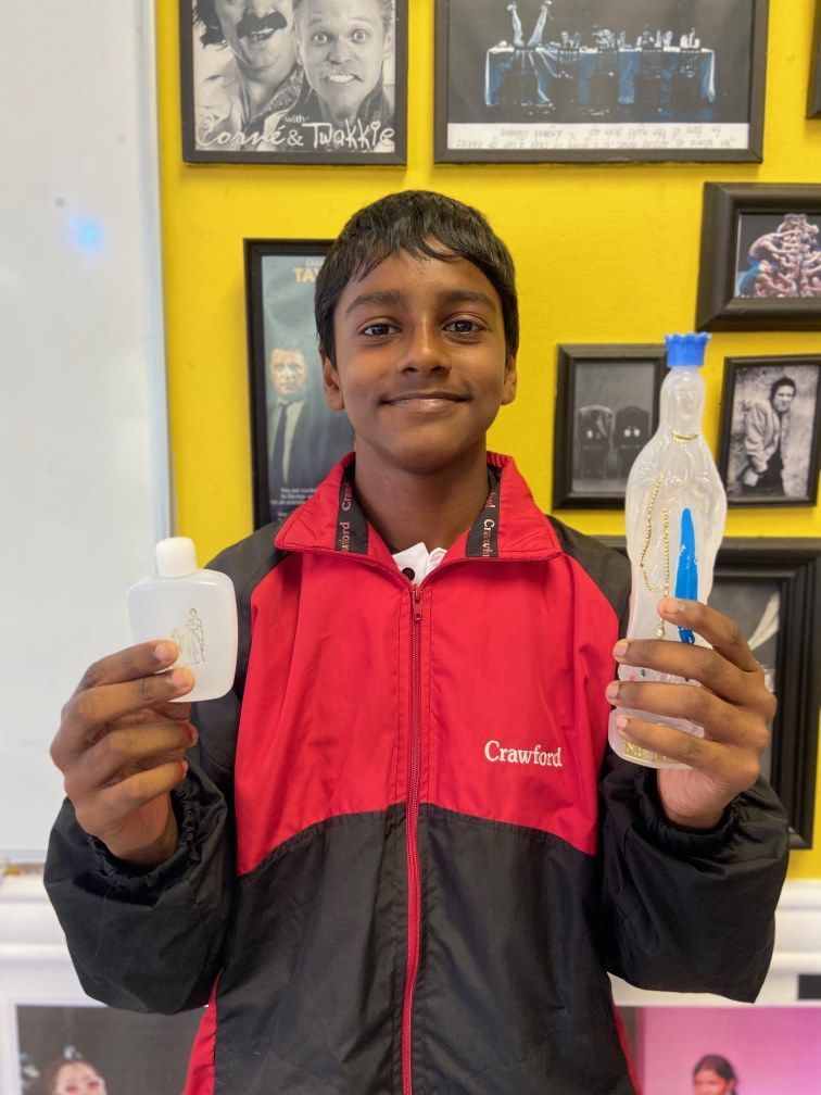 A boy in a red and black jacket is holding a bottle