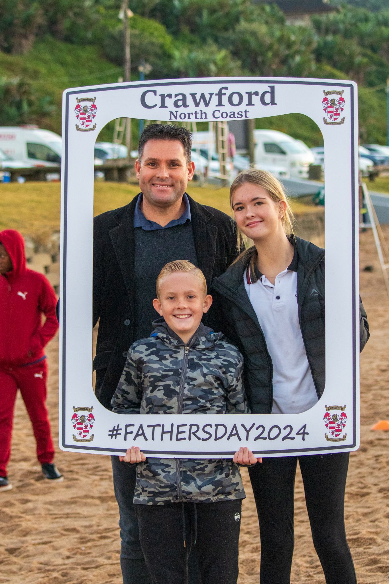 A family is posing for a picture with a father 's day photo frame.