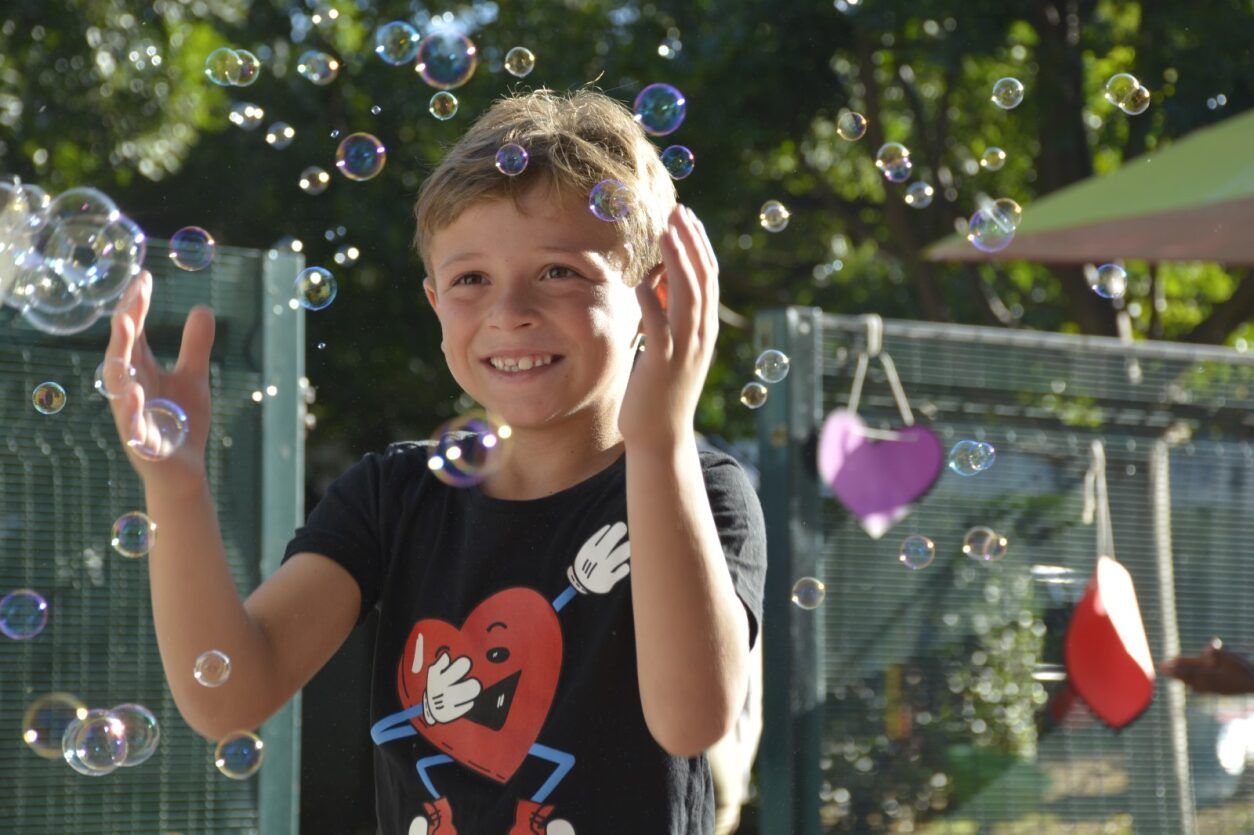 A young boy wearing a black shirt with a heart on it is playing with soap bubbles