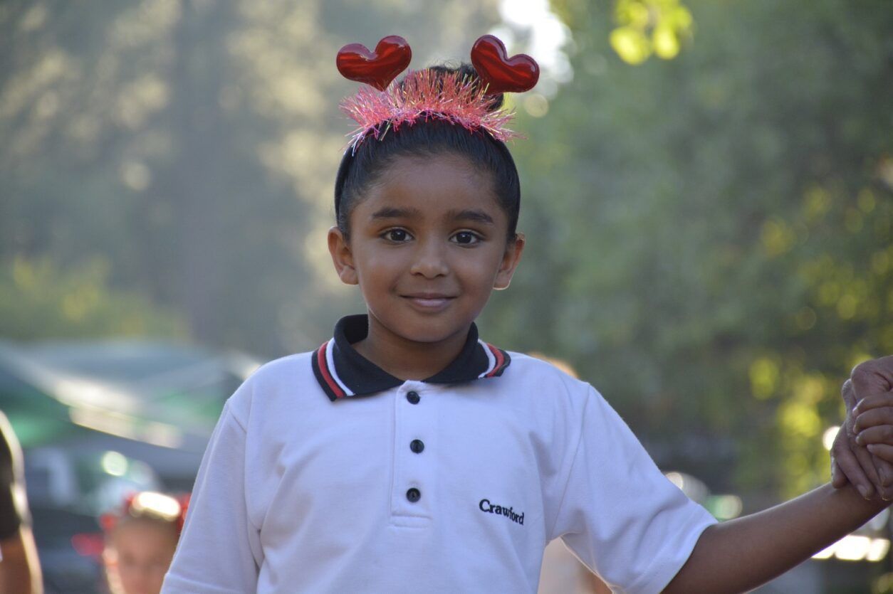 A little girl wearing a headband with hearts on it.
