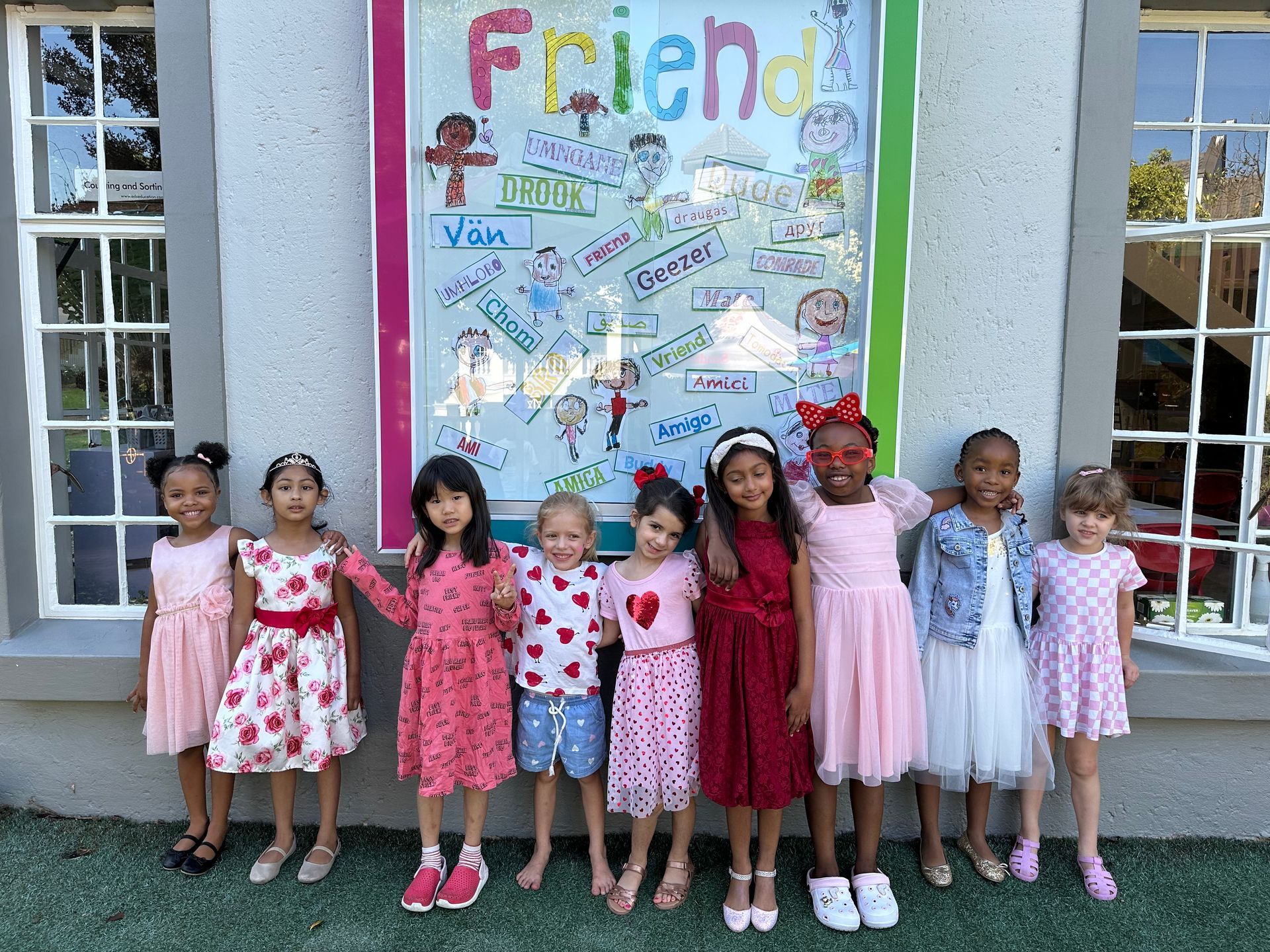 A group of young girls are posing for a picture in front of a sign that says `` friends ''.