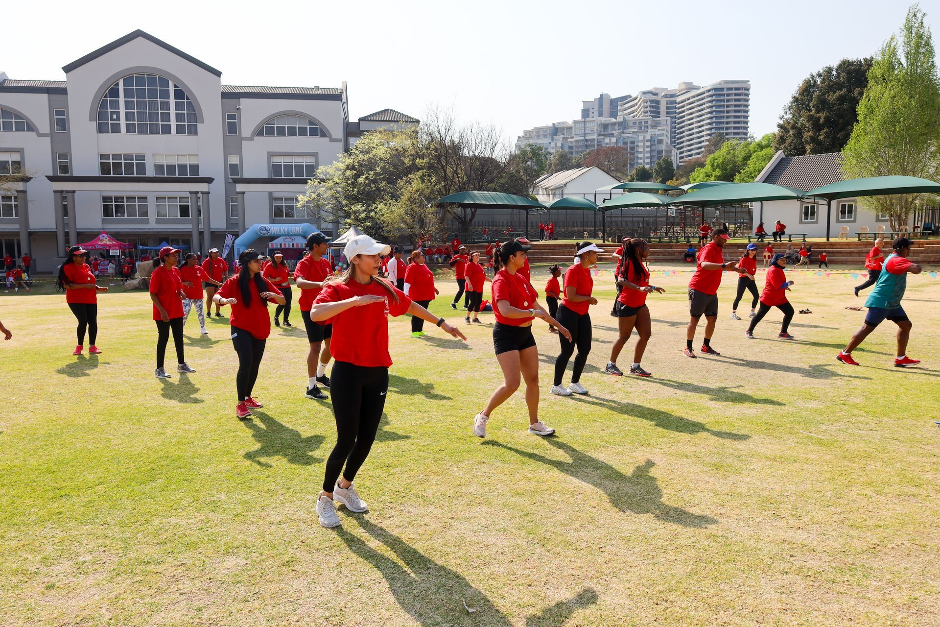 A group of people are dancing in a field in front of a building.