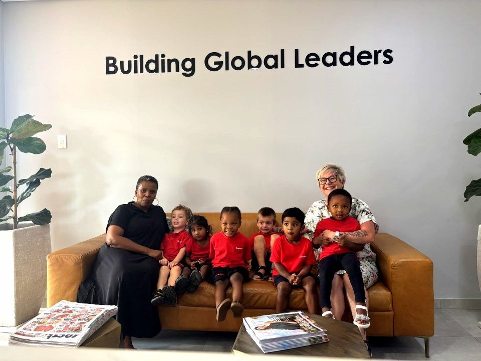 People on a brown couch in front of a wall that says 