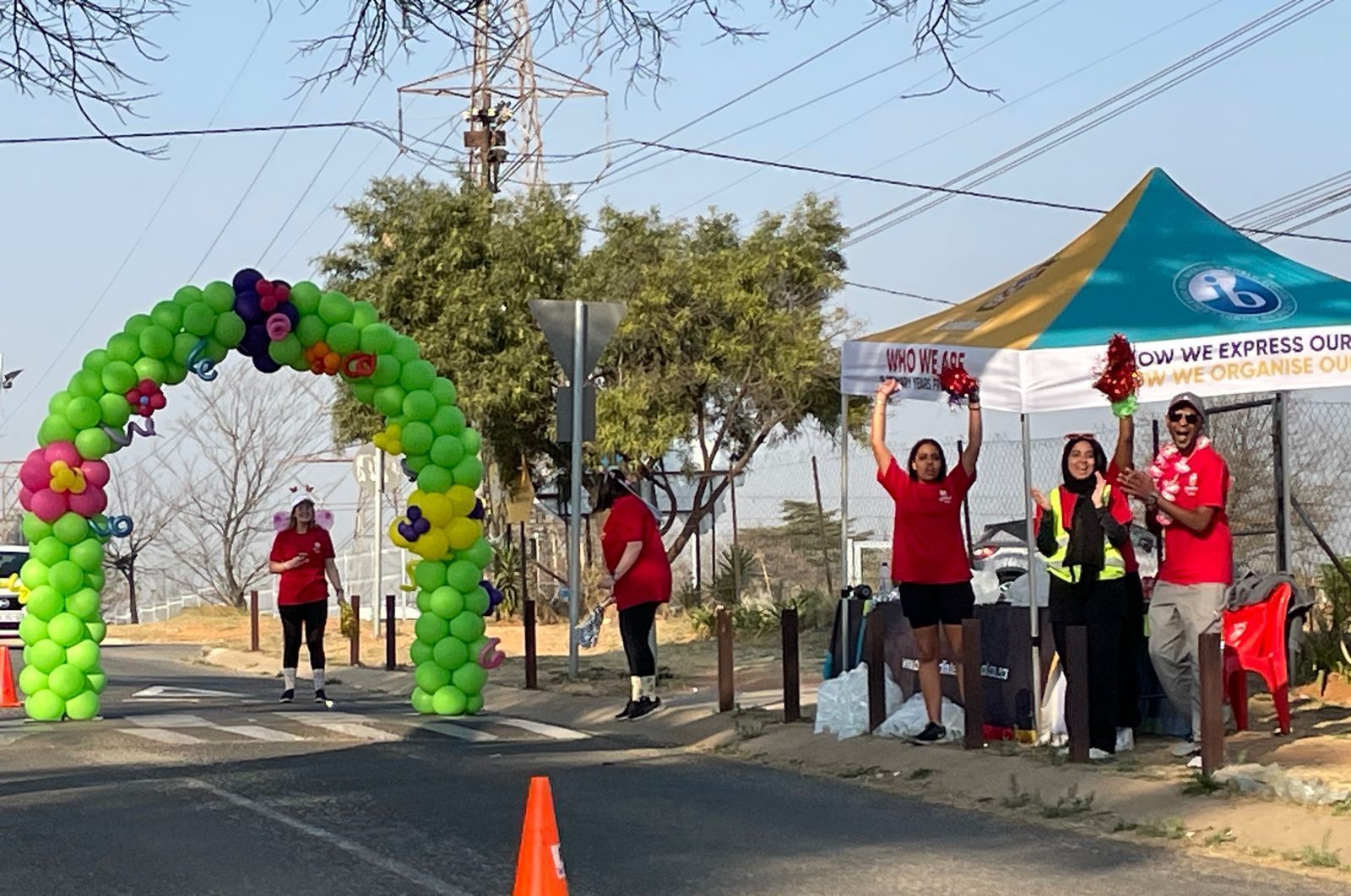 A group of people are standing in front of a green and yellow balloon arch.