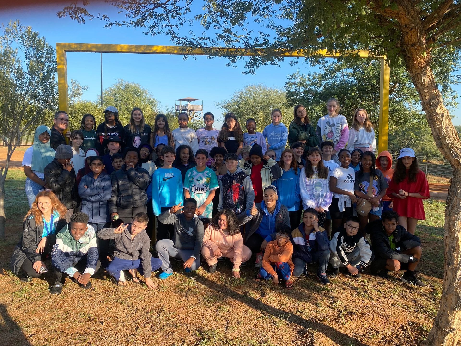 A large group of children are posing for a picture in a park.