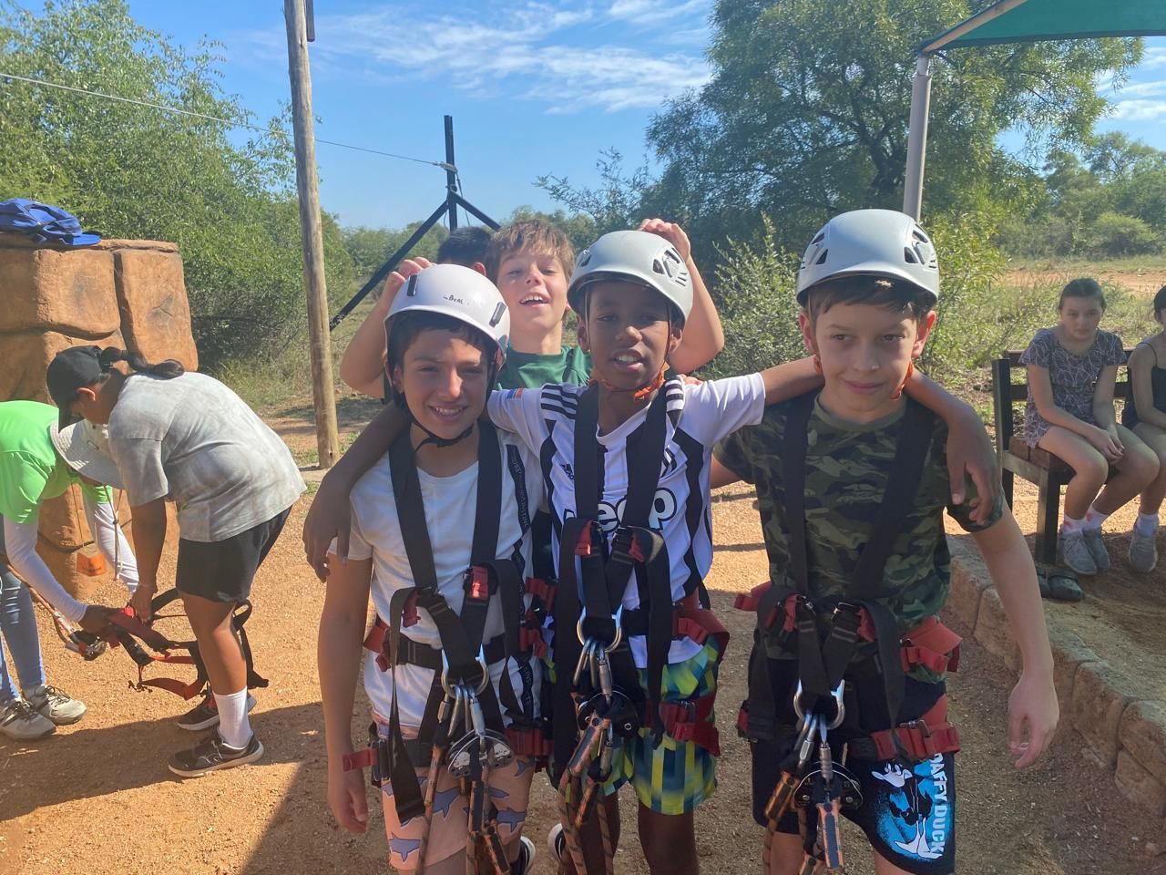 A group of young boys wearing helmets and harnesses are posing for a picture.
