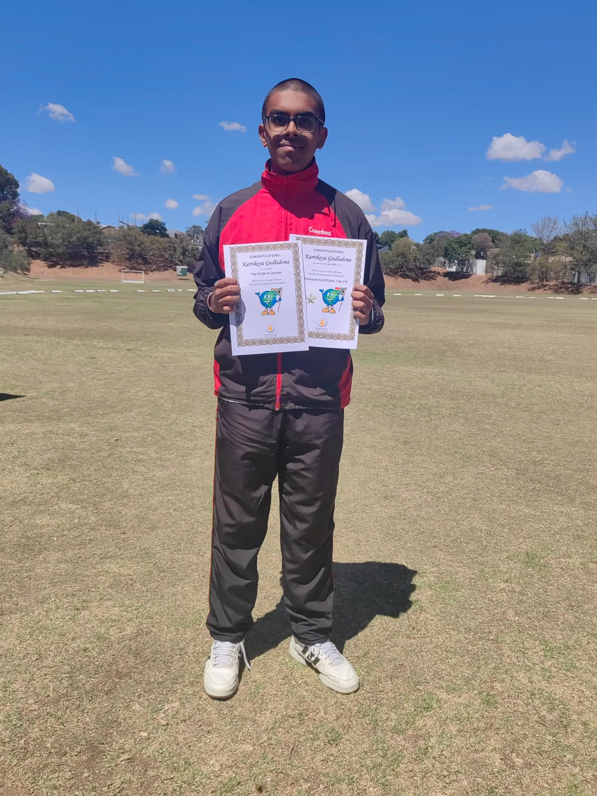 A man is standing in a field holding two certificates.