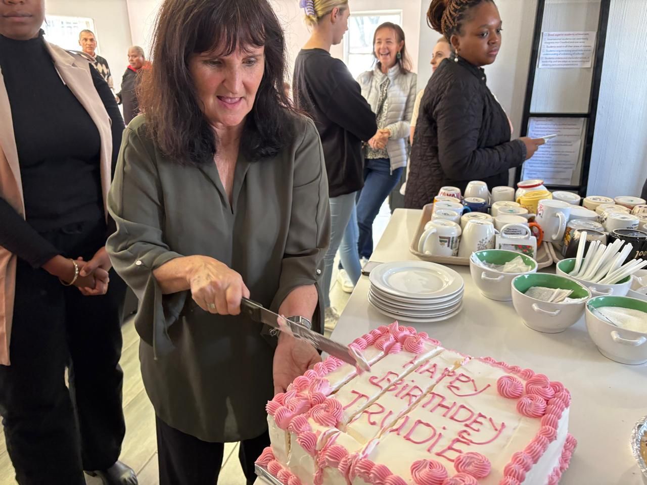 Woman cutting a birthday cake that says 