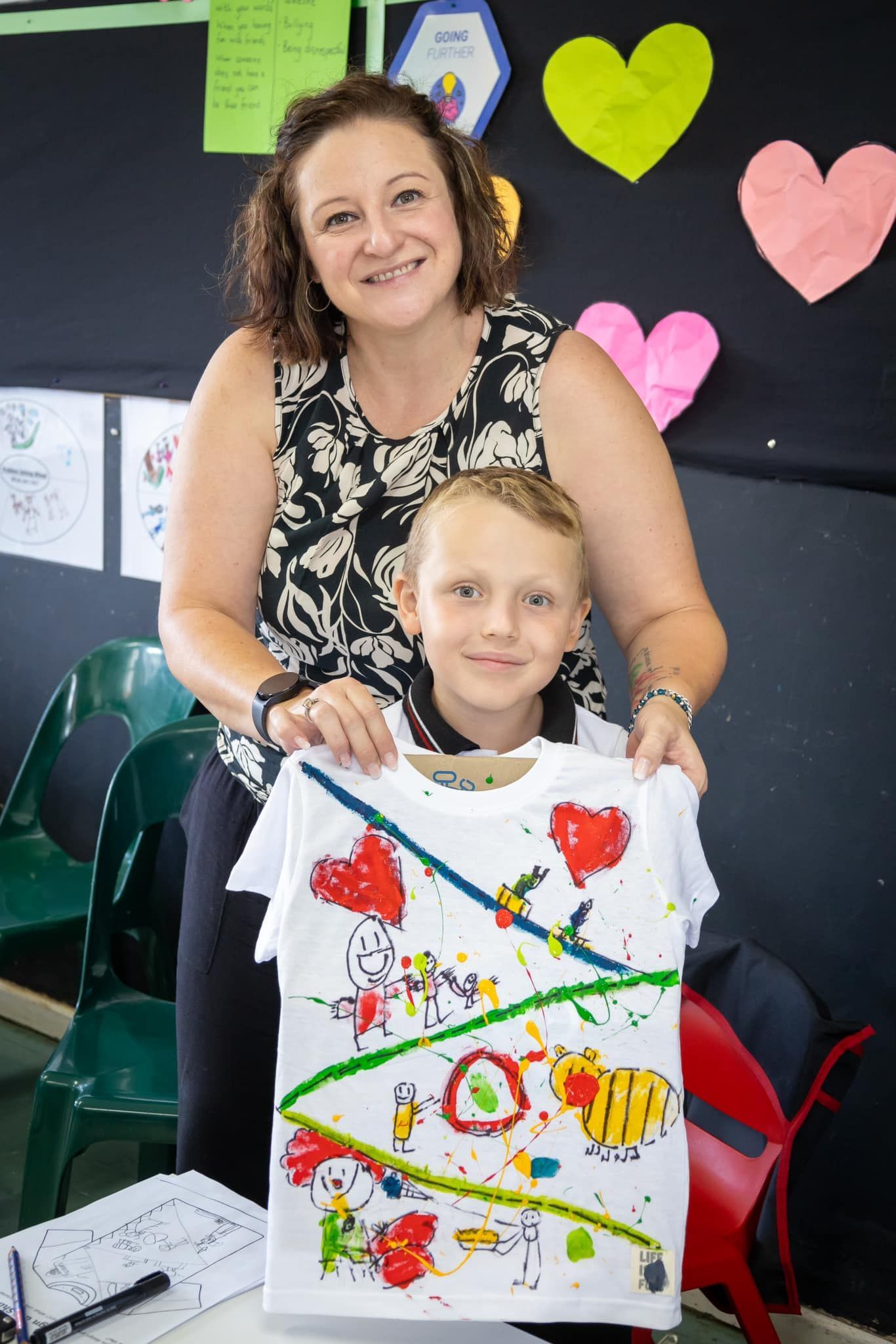 A woman and a boy are holding a shirt that has been painted.