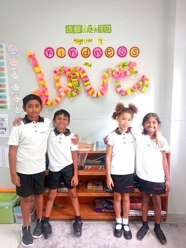 Four students pose together in a classroom; a