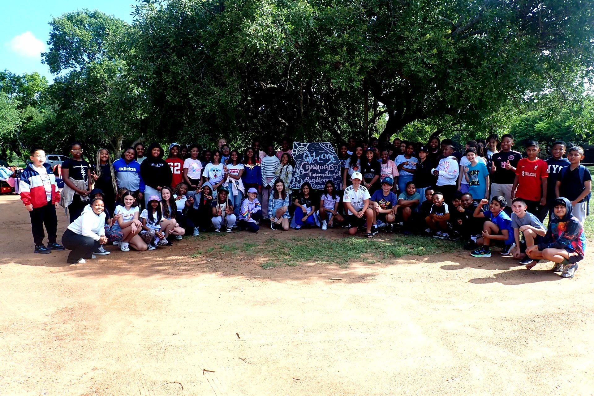Large group of people posing outdoors under a large tree.