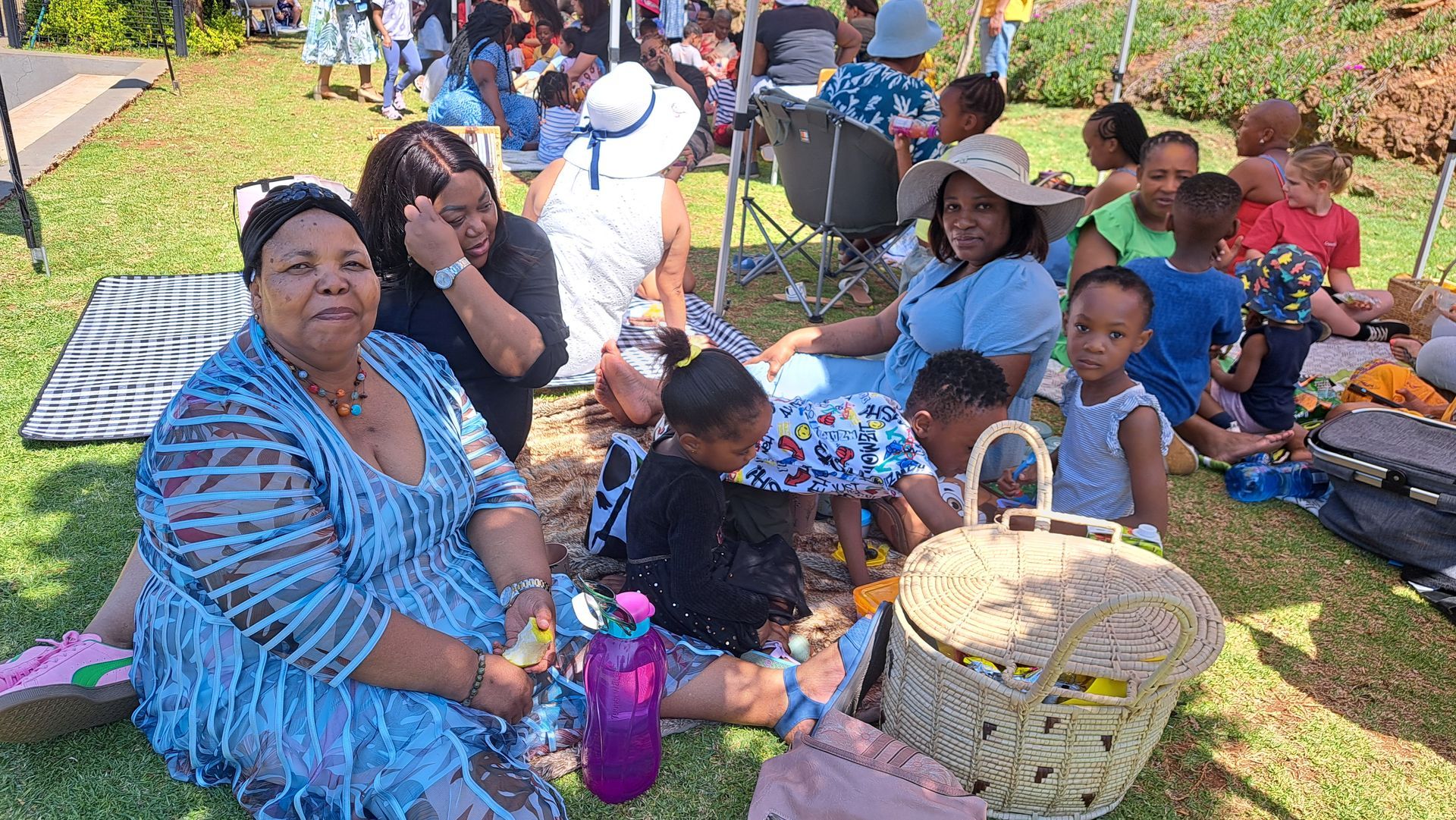 A group of people are sitting on the grass having a picnic.