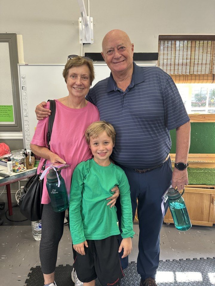A man and woman are posing for a picture with a boy in a green shirt.