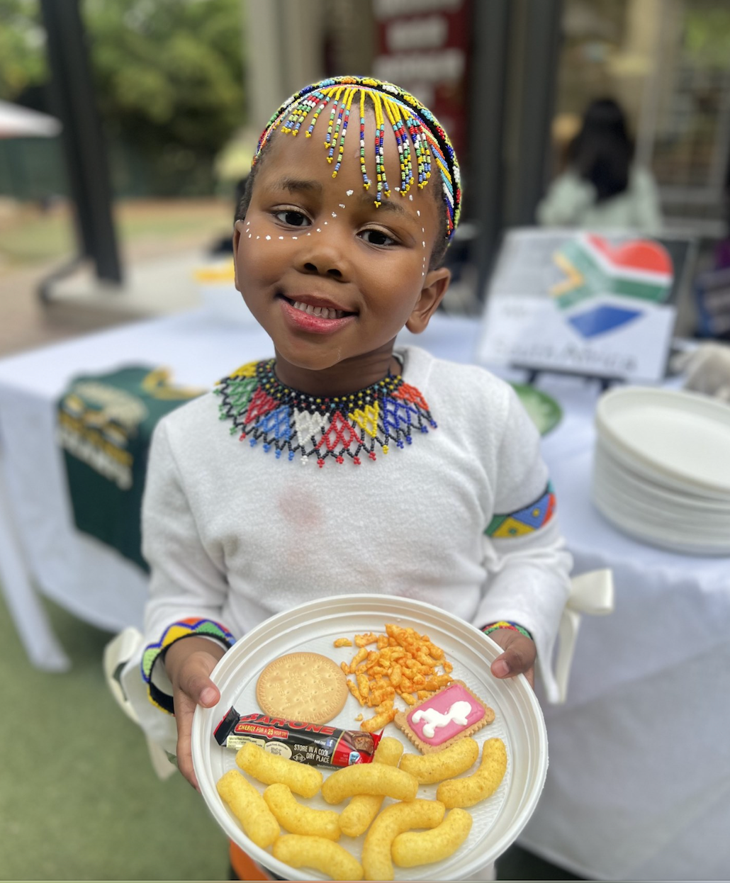 A little girl is holding a plate of food.