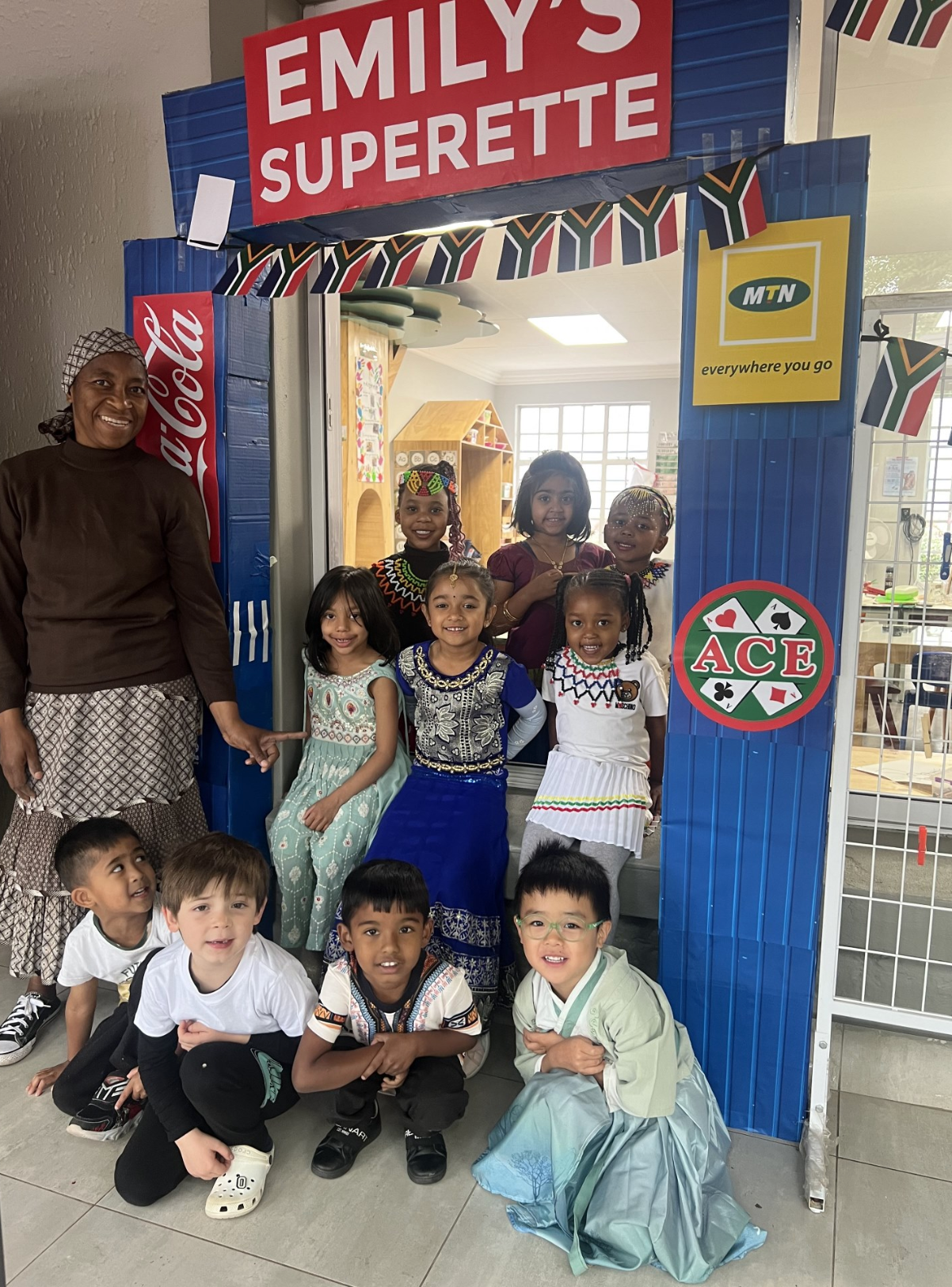 A group of children are posing for a picture under a sign that says emily 's superette