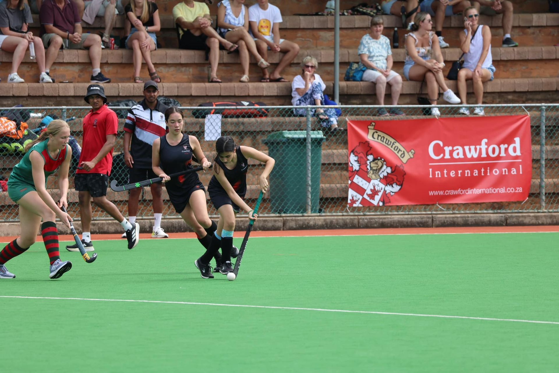 A field hockey game is being played in front of a crawford banner