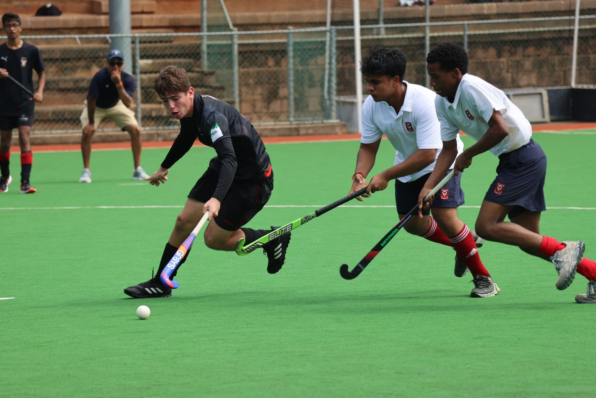 A group of young men are playing field hockey on a field.