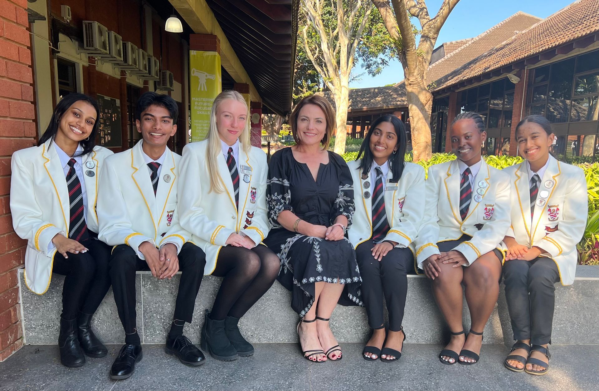 A group of people in school uniforms are posing for a picture with a woman.