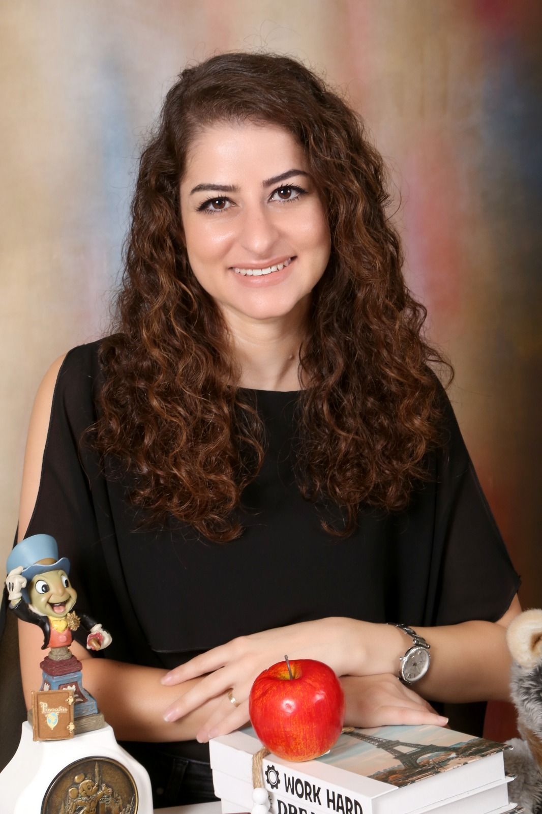 A woman is sitting at a table with a book and an apple.