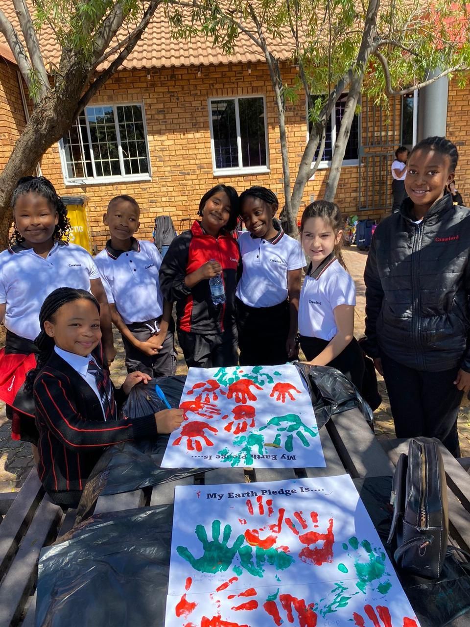 A group of children are standing around a table with handprints on it.