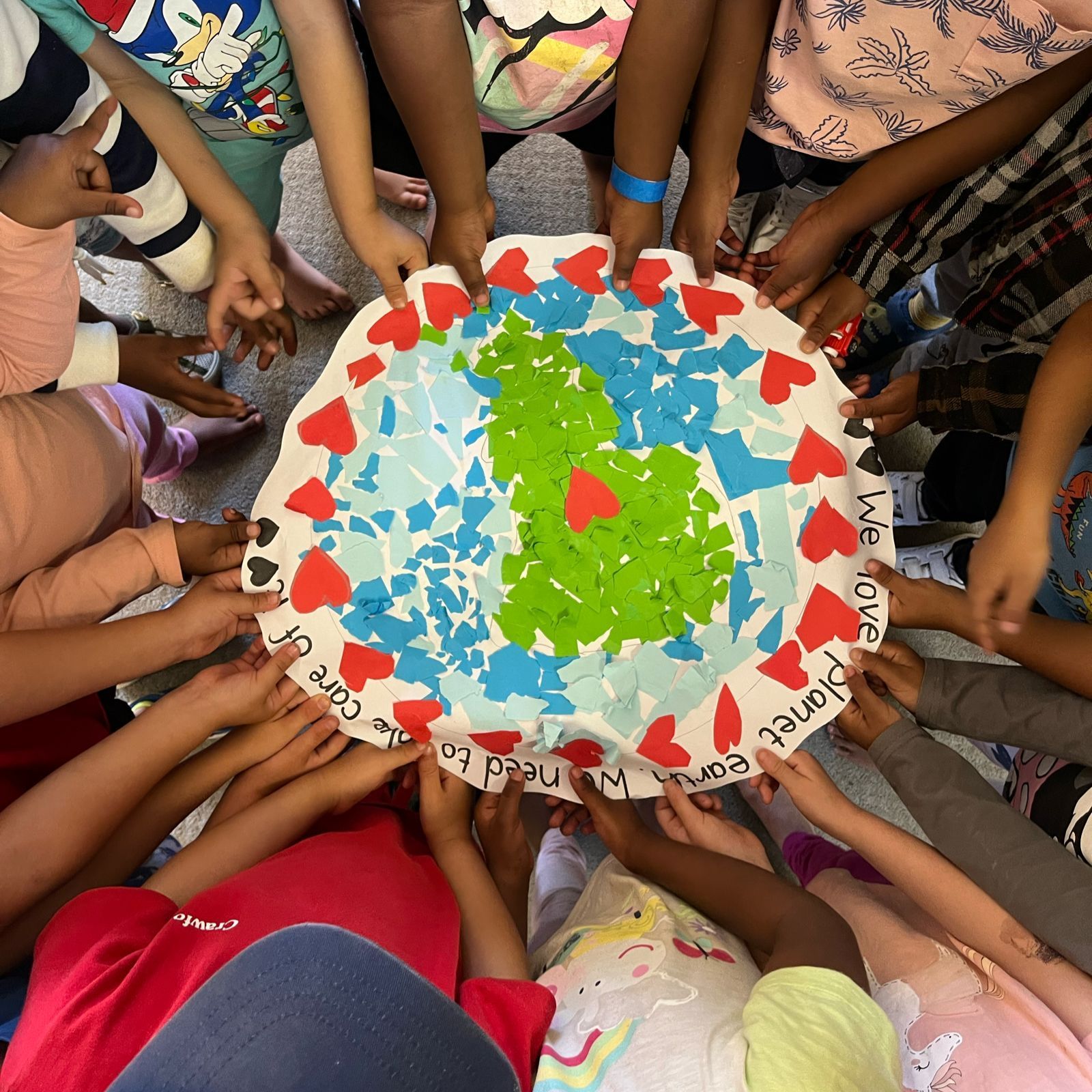 A group of children are holding a paper plate with a map of the earth on it
