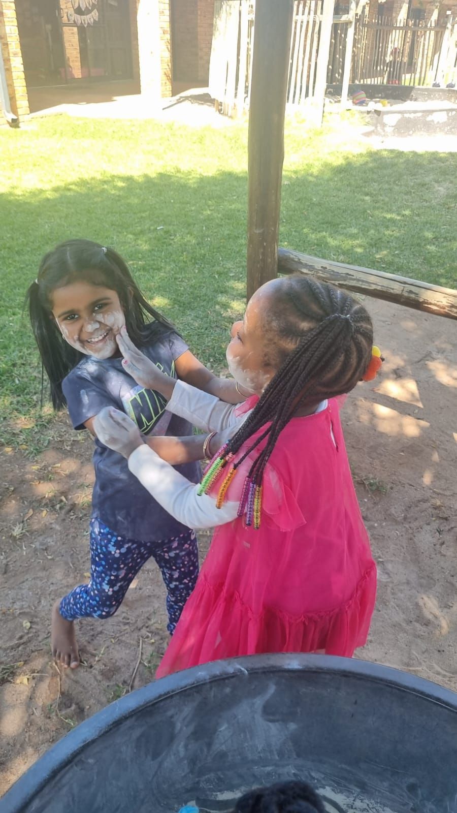 Two little girls are playing with each other in a park.
