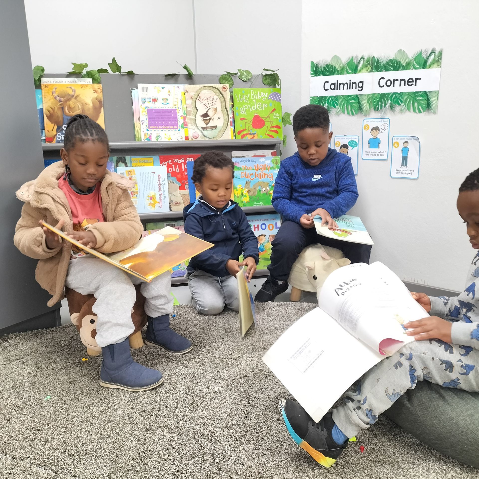 A group of children are sitting on the floor reading books in a calming corner.