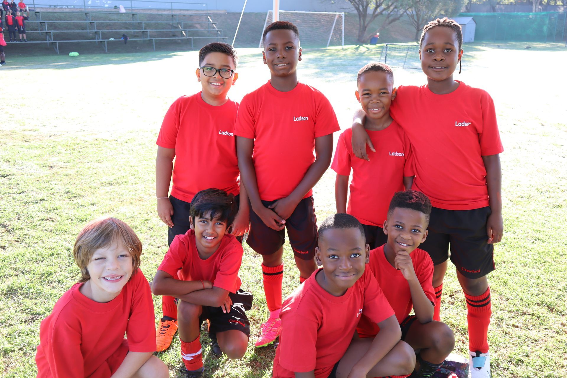 A group of young boys wearing red shirts and black shorts are posing for a picture.