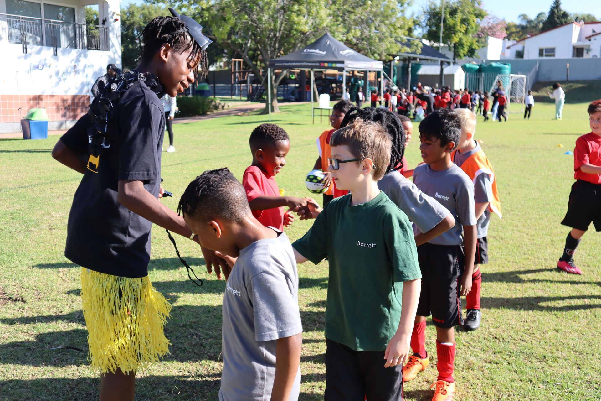 A group of young boys are standing on a field talking to each other.