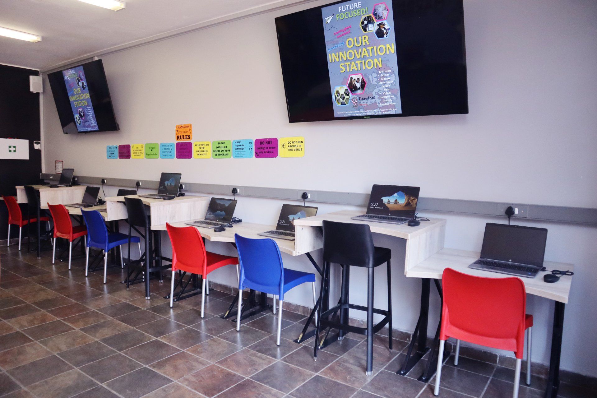 a room filled with tables and chairs with laptops on them