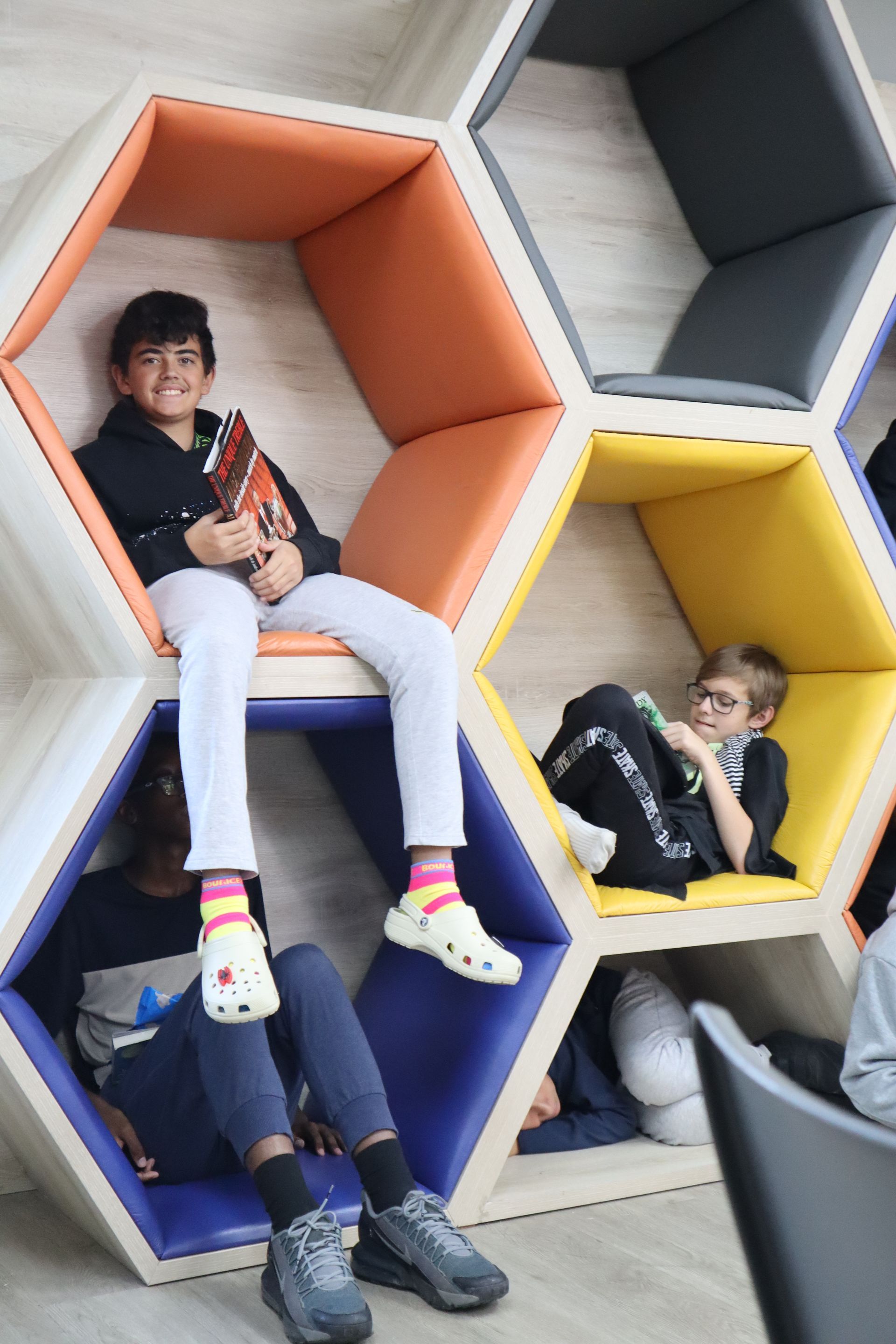 A group of children are sitting in hexagon shaped shelves.