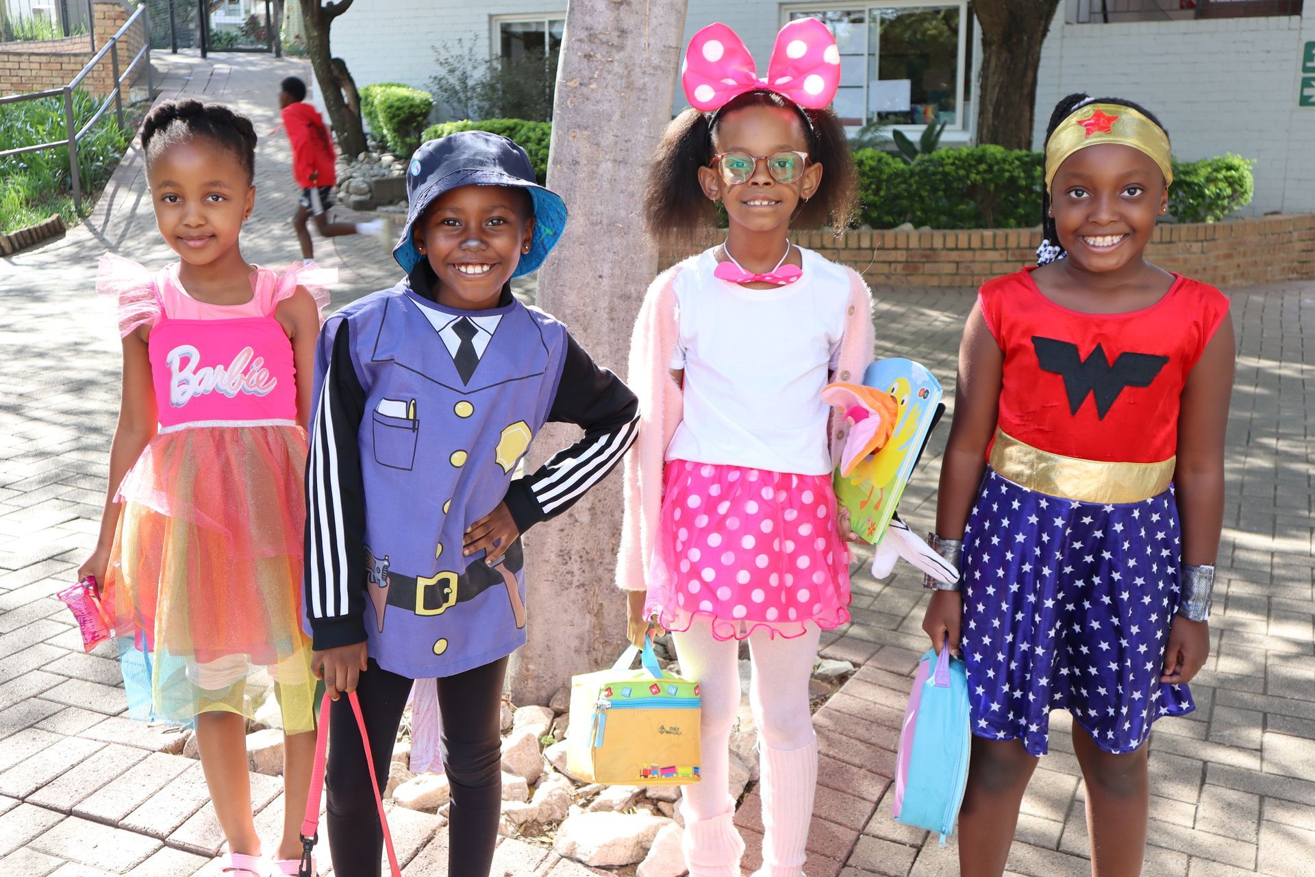 A group of young girls dressed in costumes are standing next to each other on a sidewalk.