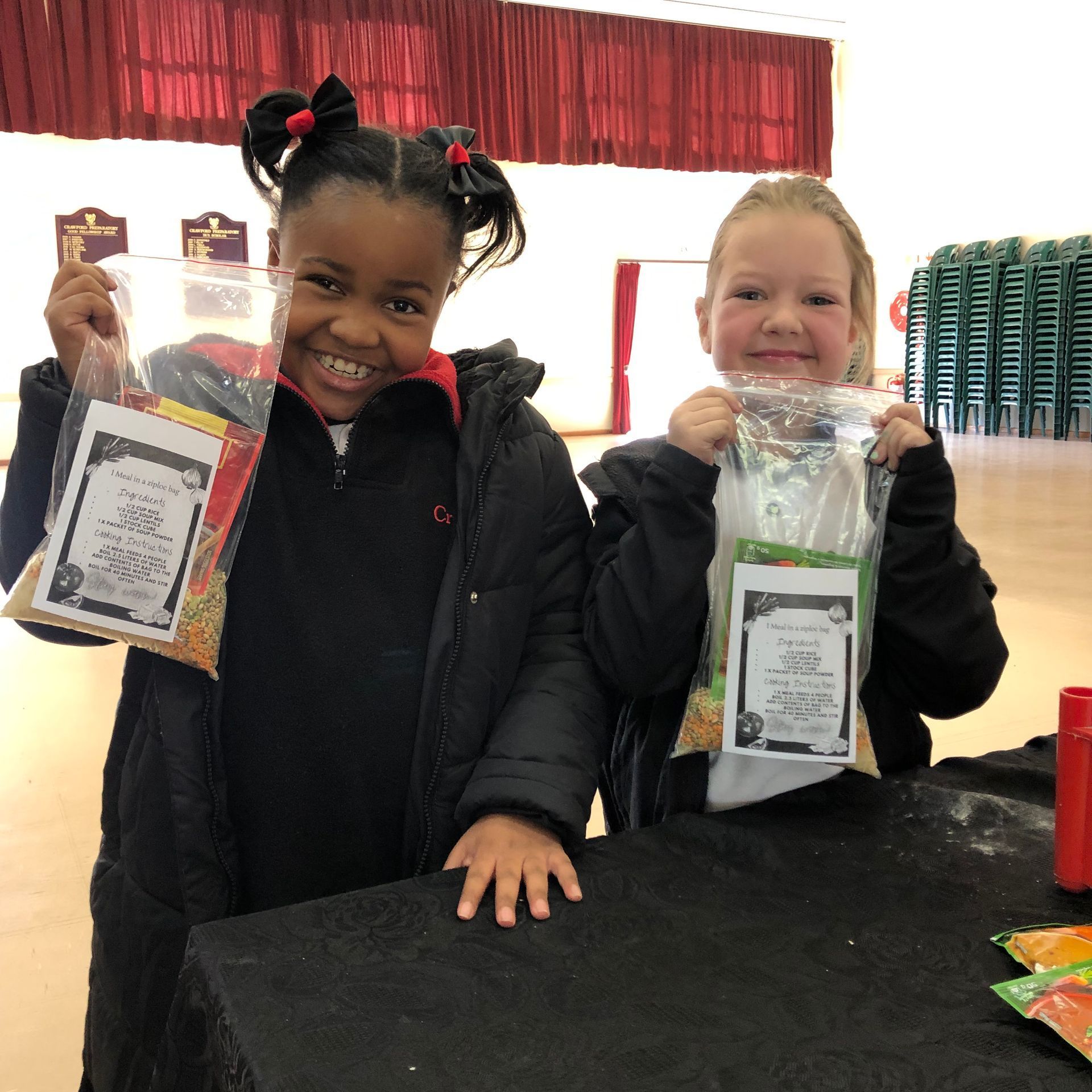Two young girls are holding bags of food and smiling for the camera