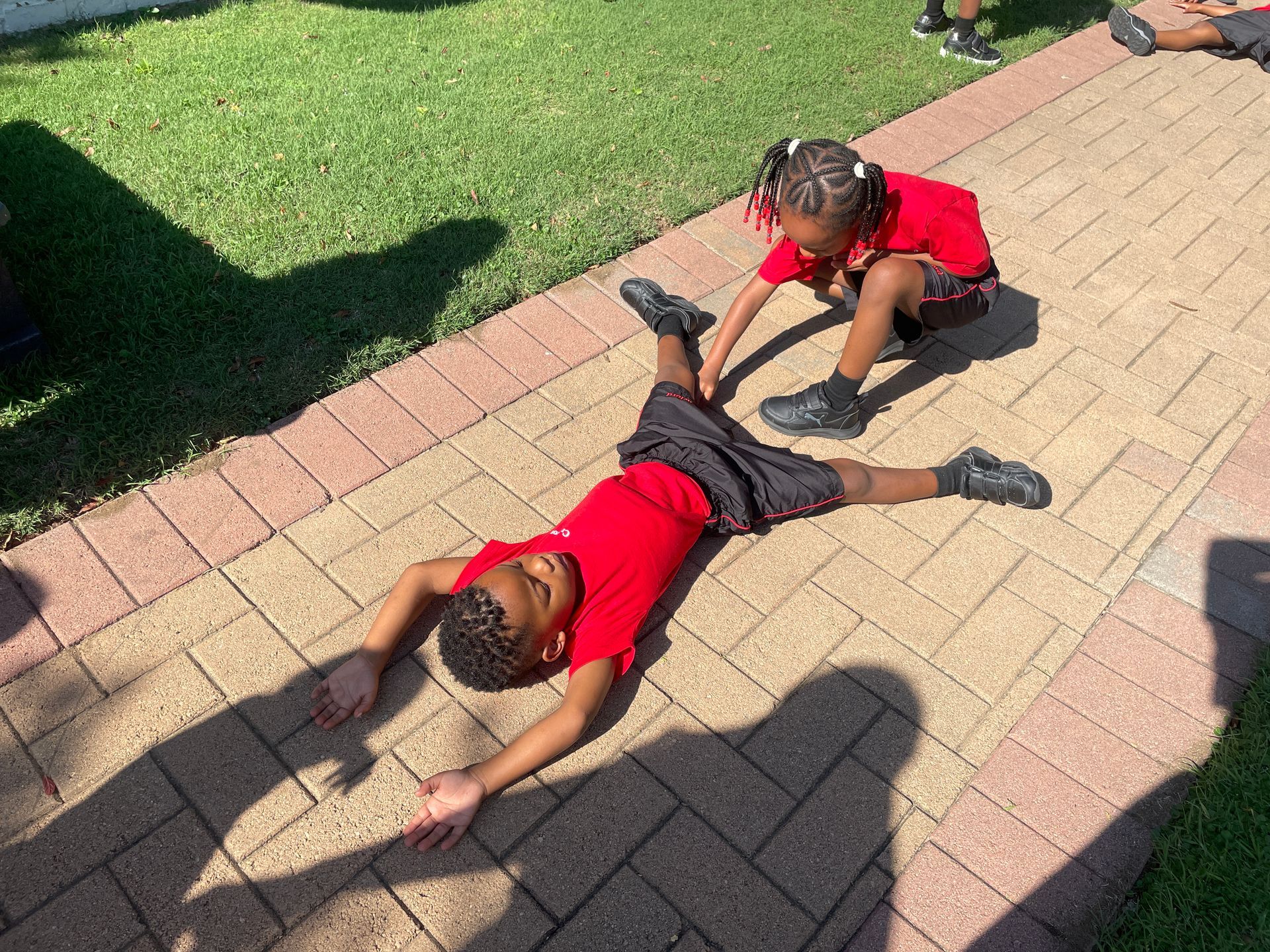 A boy and a girl are doing a handstand on a sidewalk.