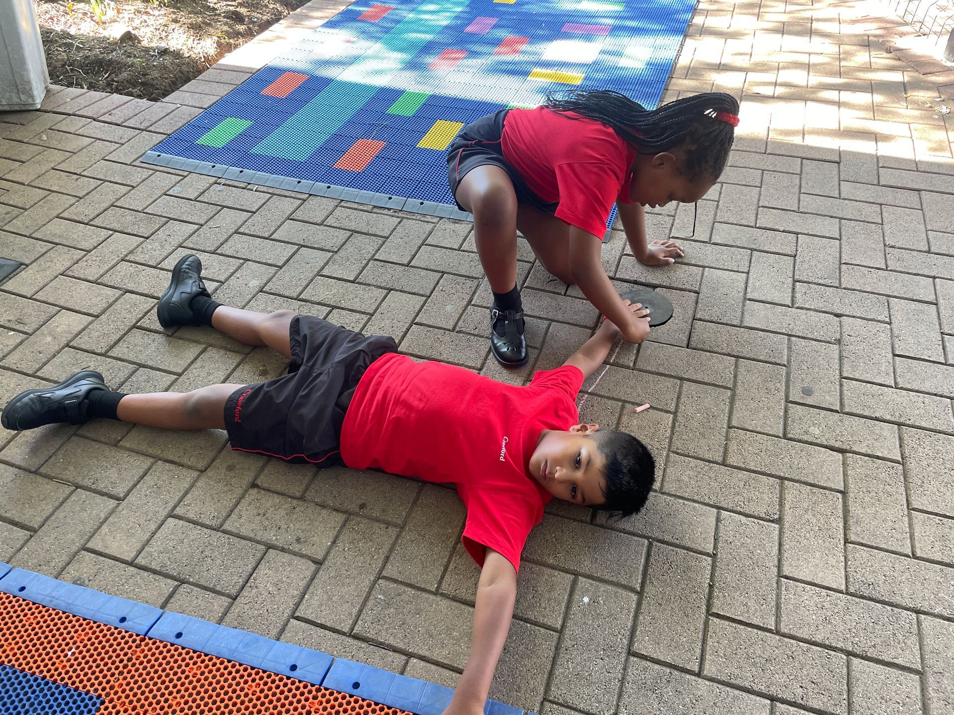 A boy and a girl are laying on the ground.